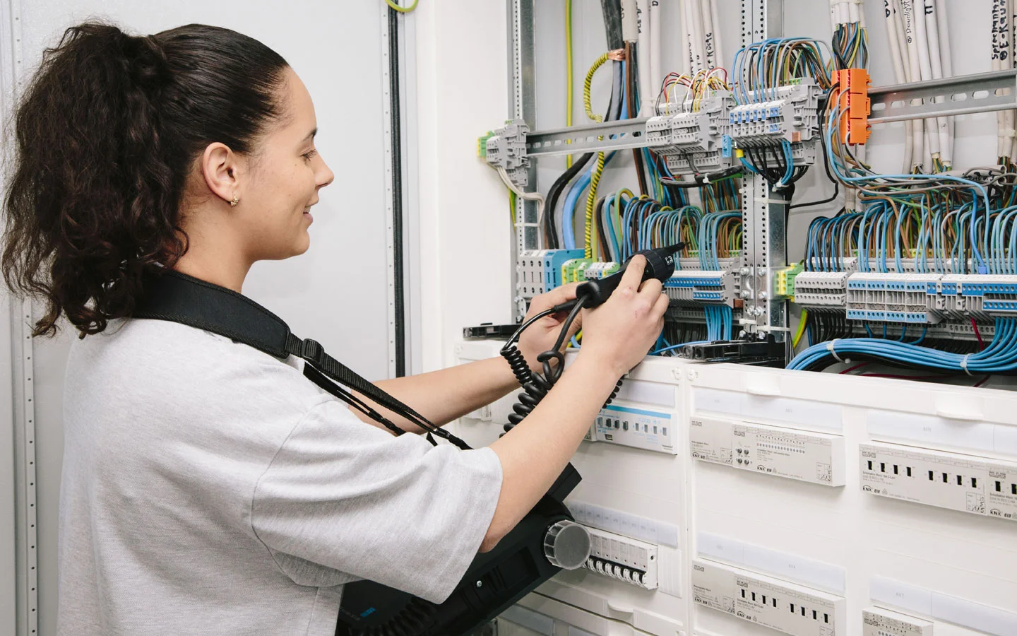 E-CHECK - Mitarbeiterin prüft im Schaltschrank mit einem Meßgerät &middot; Elektro-Diehm
