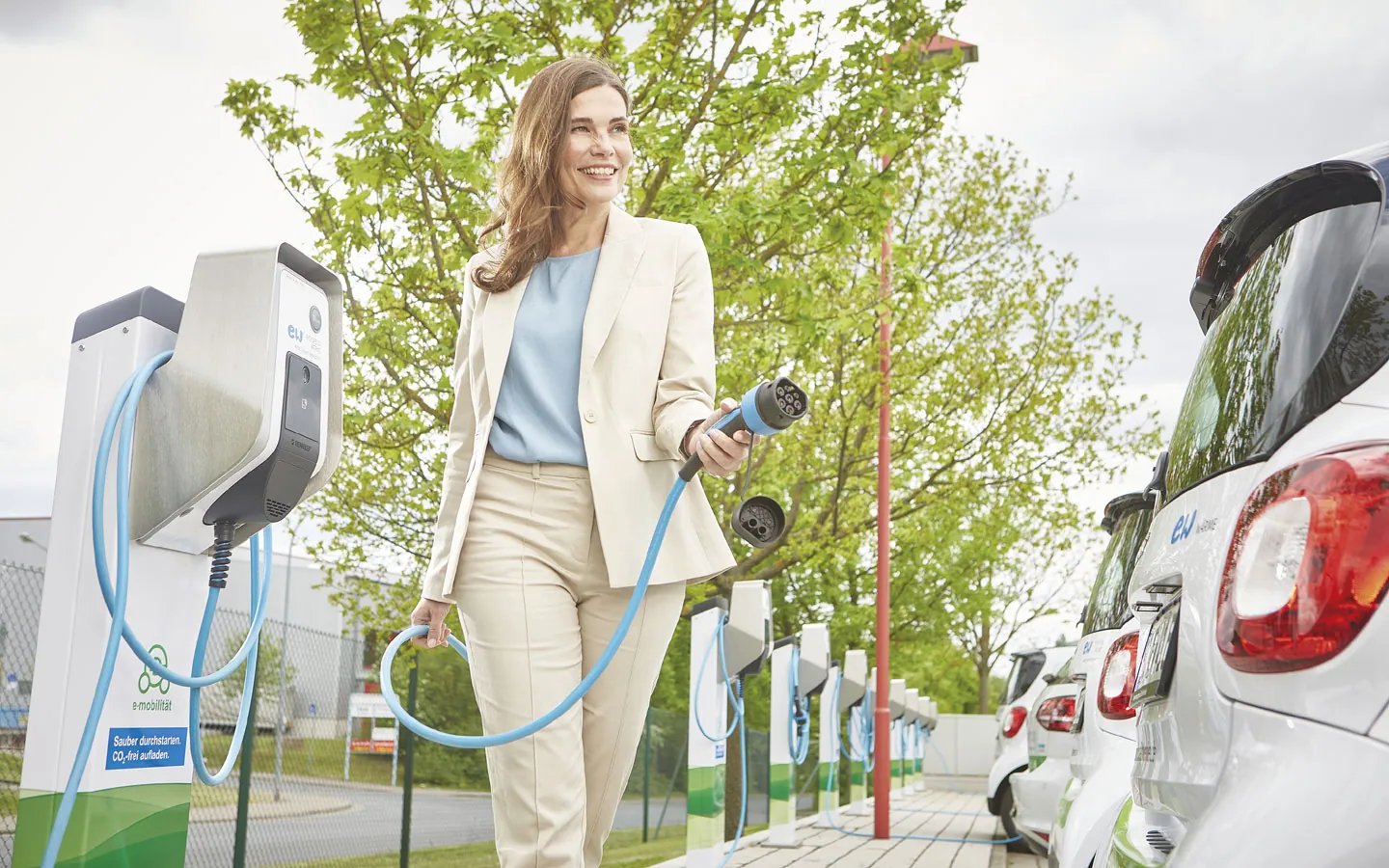 E-Mobilität - Kundin vor Ladestation mit Stecker in der Hand &middot; Elektro-Diehm